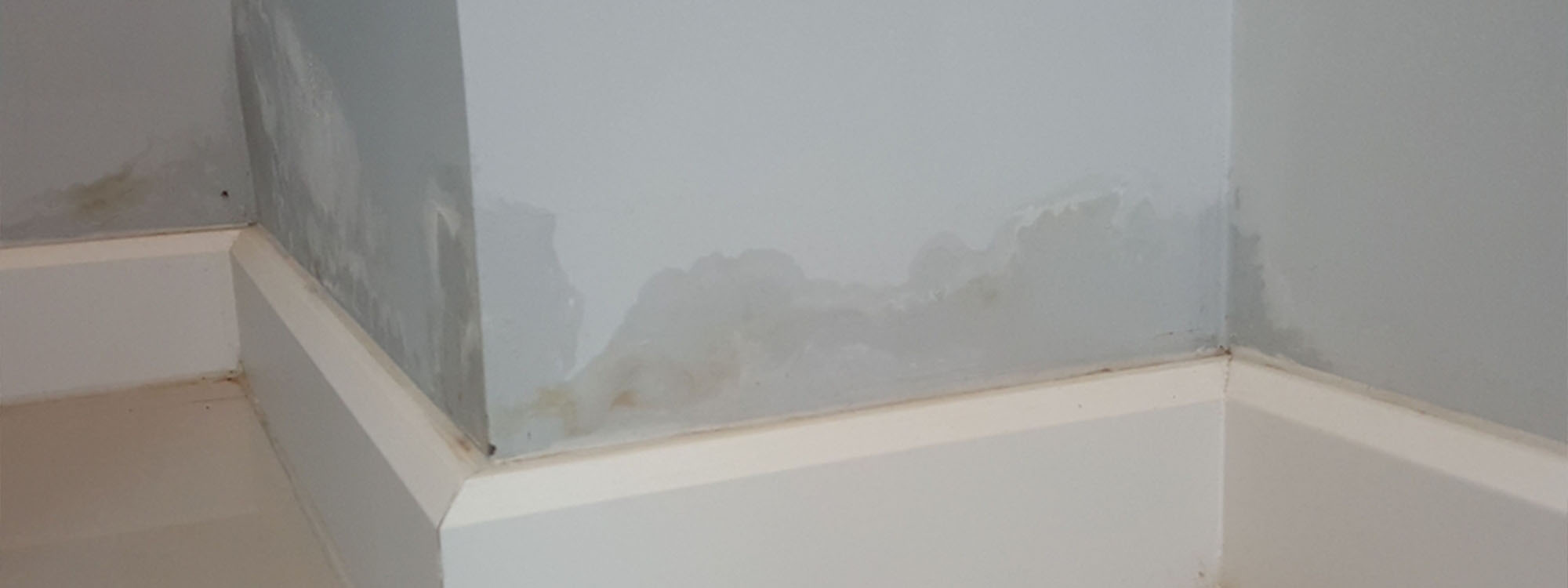 damp blue wall above floor skirting